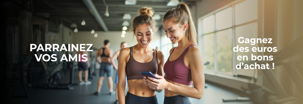 Deux femmes souriantes dans un gymnase consultent un smartphone.