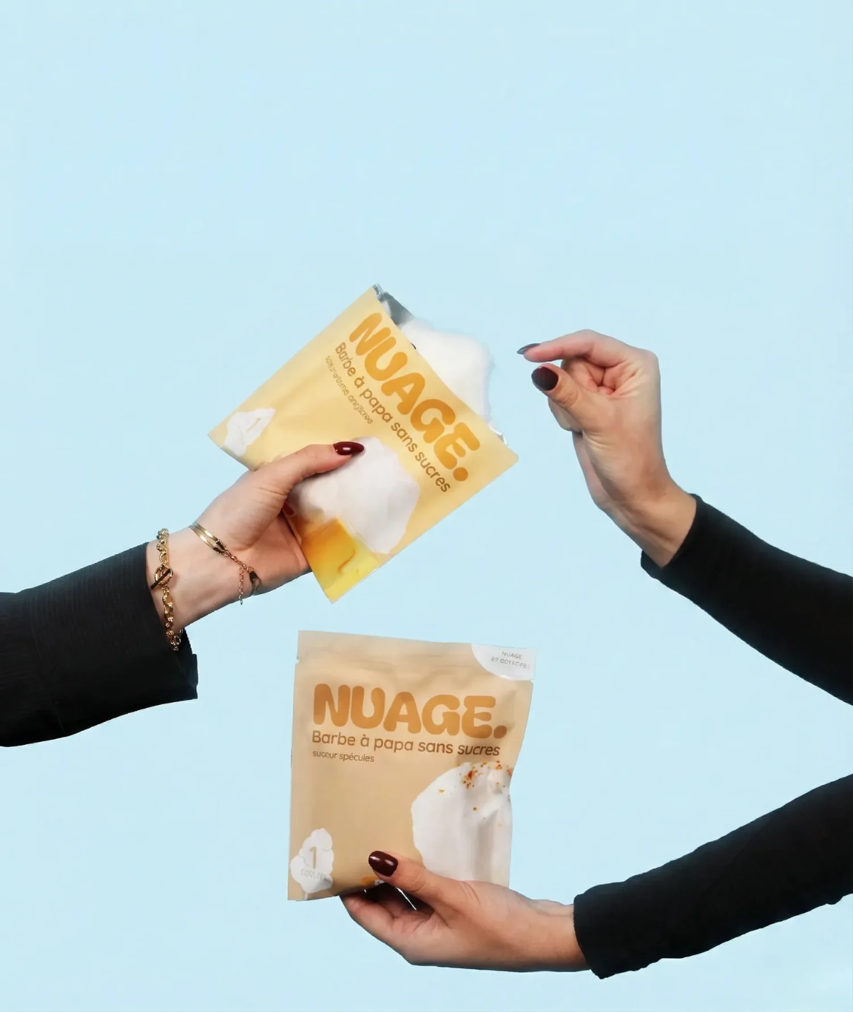 Deux mains échangent des sachets de barbe à papa sans sucres, sur fond bleu.