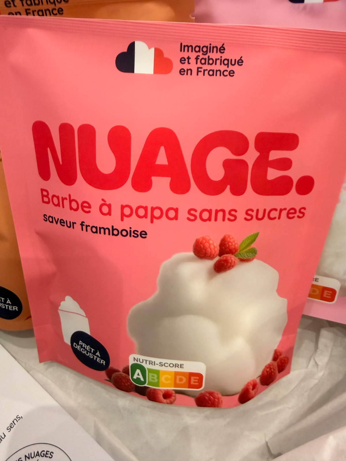 Paquet de barbe à papa sans sucres, saveur framboise, avec visuel de nuage et framboises.